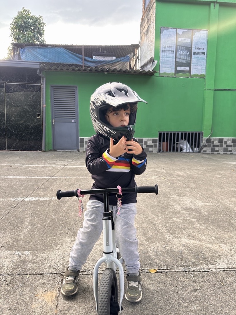 Niño usando casco integral y bici de equilibrio antes de iniciar una clase BMX